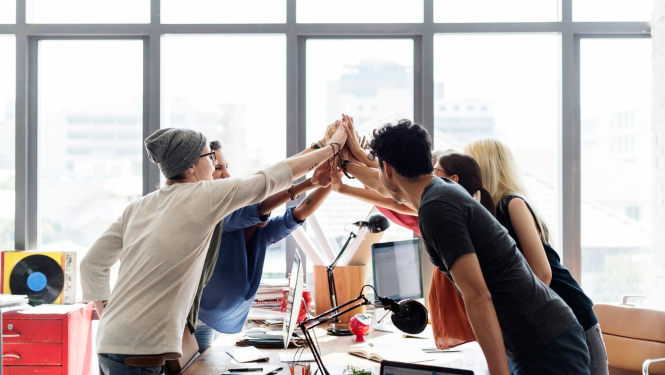 Attēlā redzami priecīgi kolēģi birojā