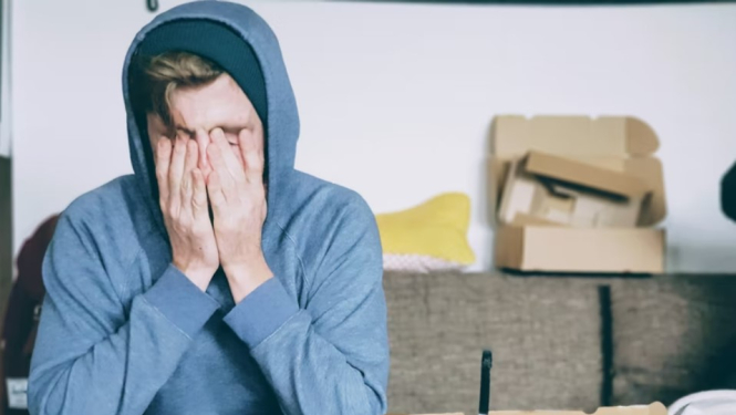 Vīrietis ar rokām aizklātu seju.