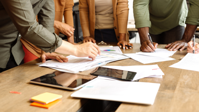 Attēlā redzami cilvēki, kuri veic plānošanas darbus. 