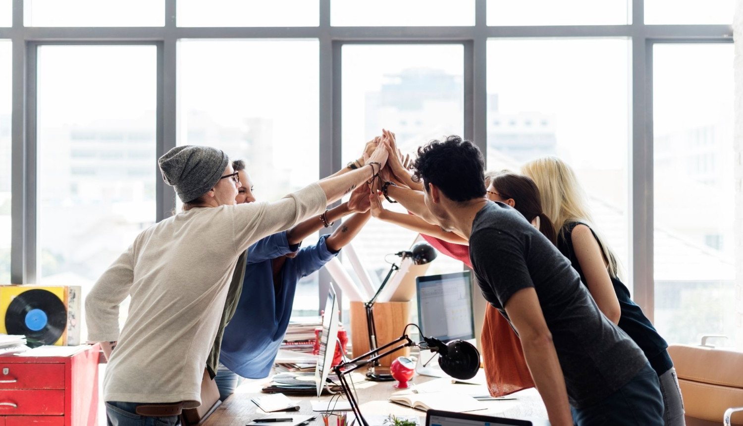 Attēlā redzami priecīgi kolēģi birojā